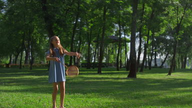 <strong>快乐的女孩</strong>打击羽毛球球拍城市公园家庭野餐时间
